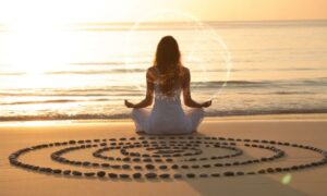 A serene woman meditating on a golden beach at sunrise, surrounded by smooth stones arranged in a spiral, symbolizing peace, awakening, and balance